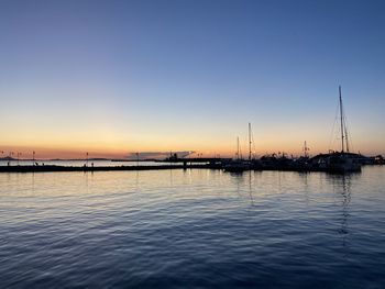 Sailboats in sea at sunset