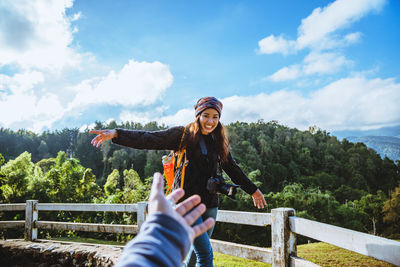 Young woman standing by railing against sky