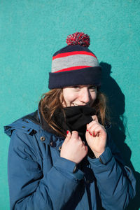 Portrait of woman in warm clothes against wall