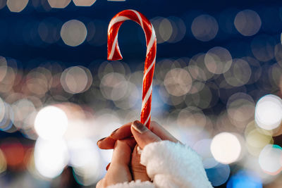 Christmas holiday magic details. female hands holding red white cane sweet lollipop