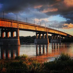 Bridge over river against cloudy sky