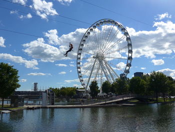 Ferris wheel by river against sky