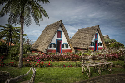 House by palm trees on field against sky