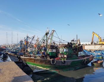 Boats moored at harbor against clear sky