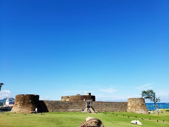 Built structure on field against clear blue sky