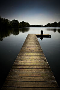 Pier over lake against sky during sunset