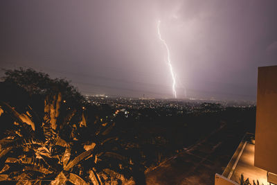 Lightning over cityscape against sky