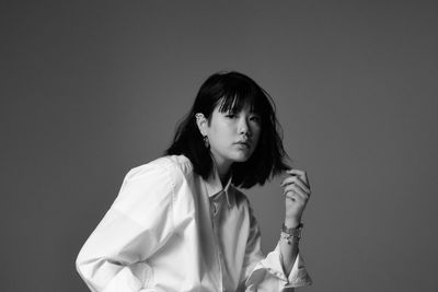 Portrait of woman standing against gray background