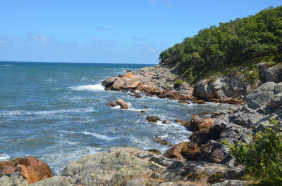 Scenic view of rocks by sea against sky