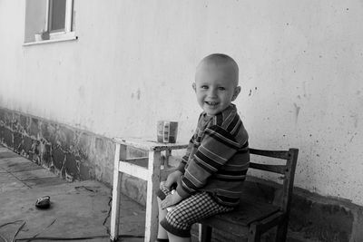 Portrait of boy smiling while sitting at table against wall