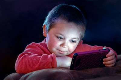 Young boy happily watching cartoons on moms cell phone