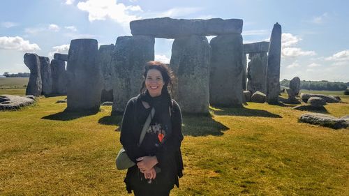 Portrait of smiling woman standing against old ruins