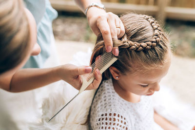 High angle view of woman hairstyling daughter