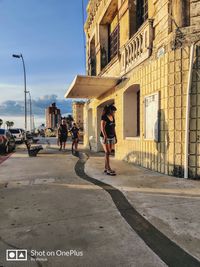 People walking on sidewalk by street in city