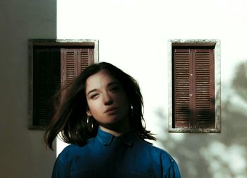 Portrait of beautiful young woman standing against building