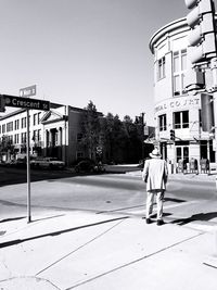 Rear view of man walking on road along buildings