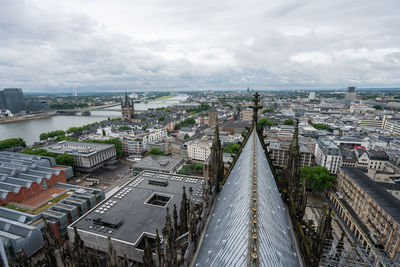 Aerial view of cologne cathedral and buildings in city against cloudy sky