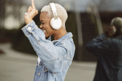 Cheerful woman enjoying music on wireless headphones