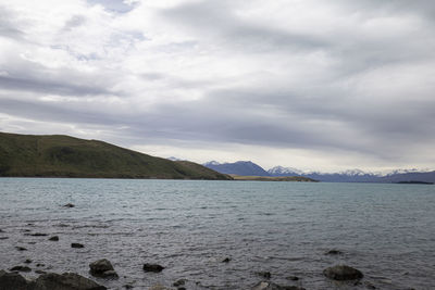 Scenic view of lake by mountains against sky