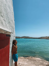 Man standing by sea against blue sky