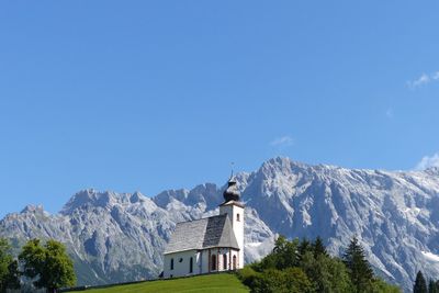 Low angle view of building on hill against mountains and sky during sunny day