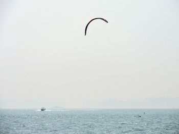 Bird flying over sea against clear sky