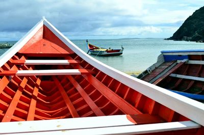 Boats in sea against cloudy sky