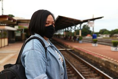 Woman wearing mask standing on railroad station platform