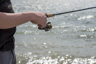 Midsection of man fishing in sea