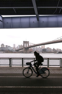 Man riding bicycle on bridge in city