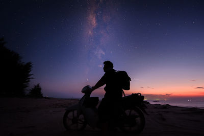 Silhouette man standing on beach against sky at night