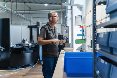 Engineer with work tool reading document while standing at factory