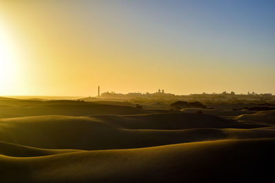 Scenic view of desert against clear sky during sunset