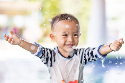 Cute boy with arms raised in swimming pool