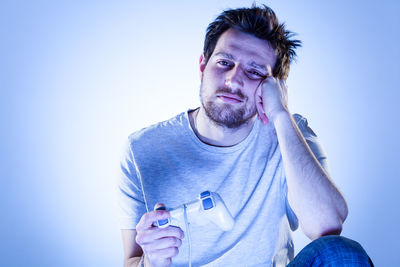 Portrait of young man standing against blue background