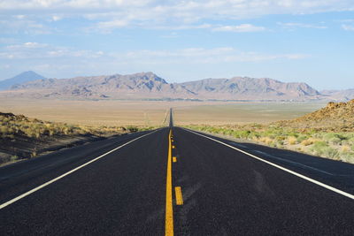 Empty road by mountains against sky
