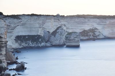 Rock formations in sea against clear sky