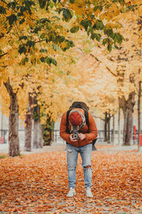 Full length of woman standing on autumn leaves