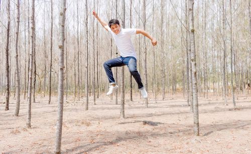 Full length portrait of man jumping in forest