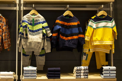 Shirts and pants hanging on hangers on a clothing rack and arranged in a shelf in a clothing store