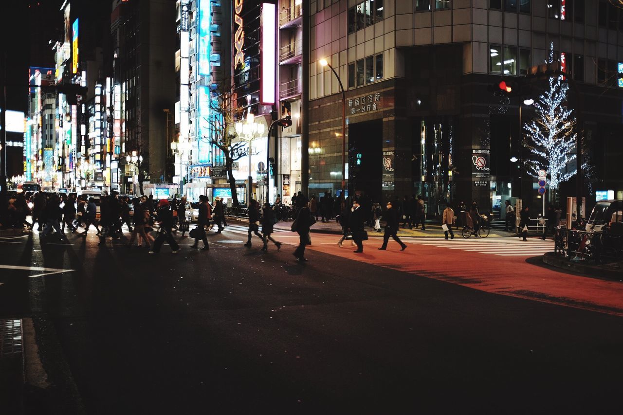 building exterior, city, architecture, street, built structure, night, illuminated, city street, city life, road, car, transportation, building, land vehicle, street light, incidental people, outdoors, mode of transport, sidewalk