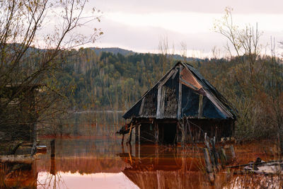 Abandoned house by cyanide lake against mountains and sky