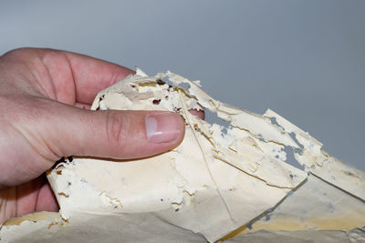 Close-up of hand holding ice cream over white background