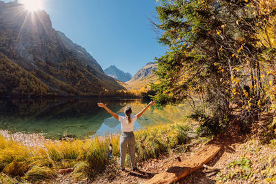 Rear view of woman standing by lake against sky