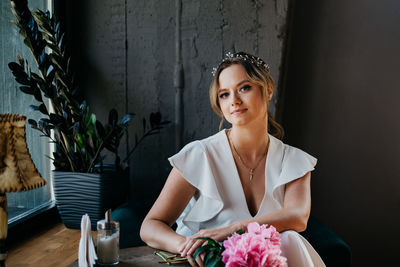 Portrait of beautiful woman sitting against wall