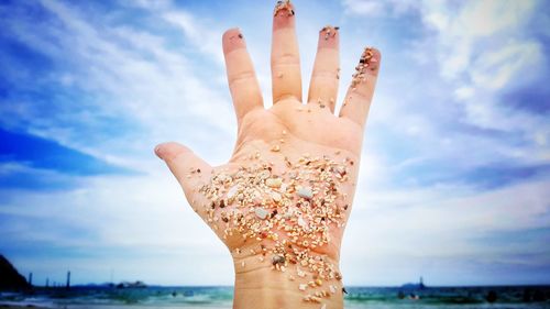 Close-up of woman hand against sky