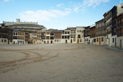 Empty street amidst buildings in town against sky