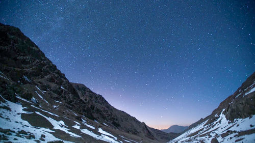 Scenic view of snowcapped mountains against sky at night