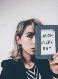 Close-up portrait of woman with text placard at home