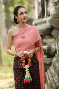Smiling young woman with floral garland standing temple